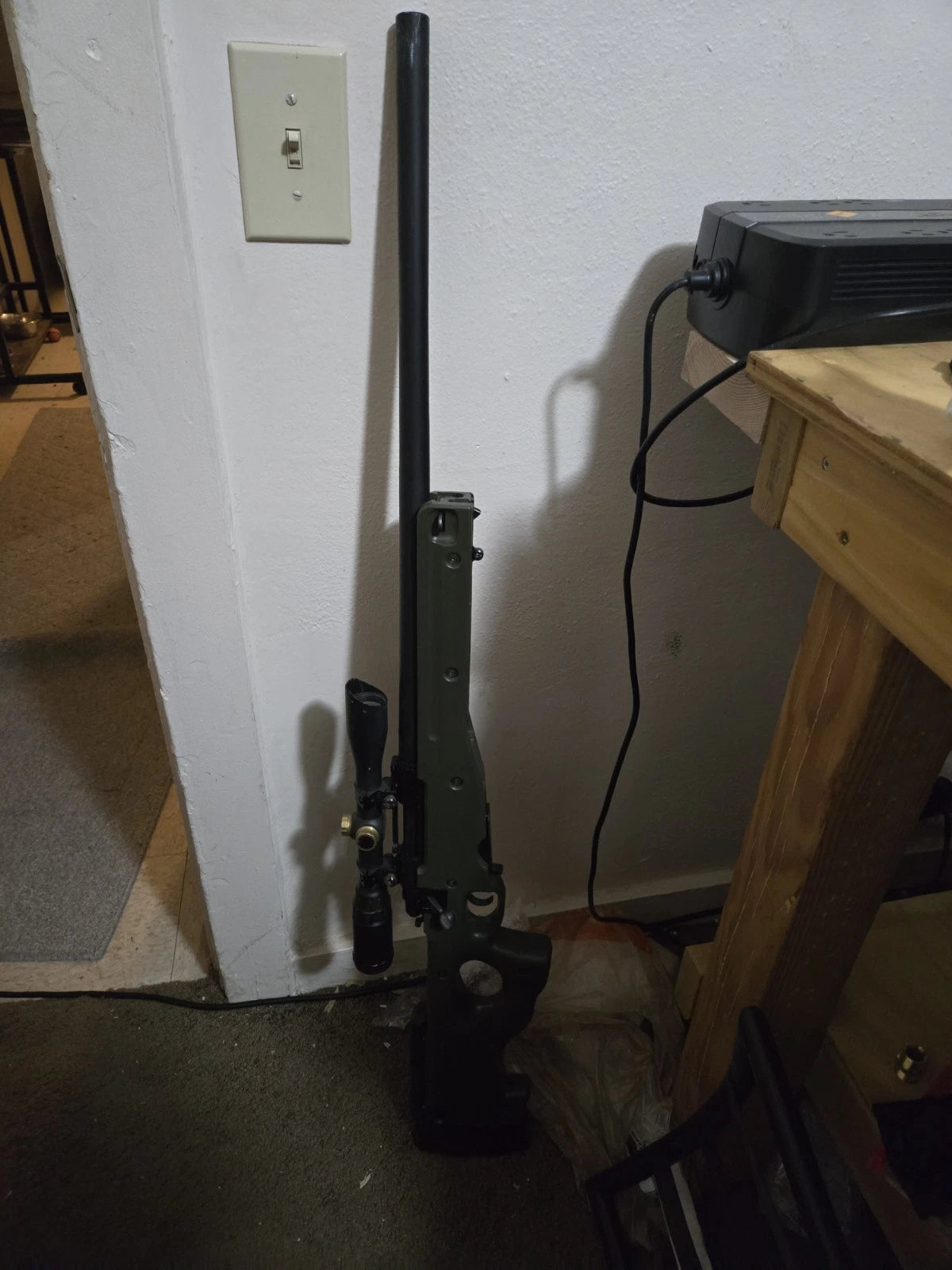 Tanaka M700 AICS Sniper Rifle in OD Green leaning against a wall