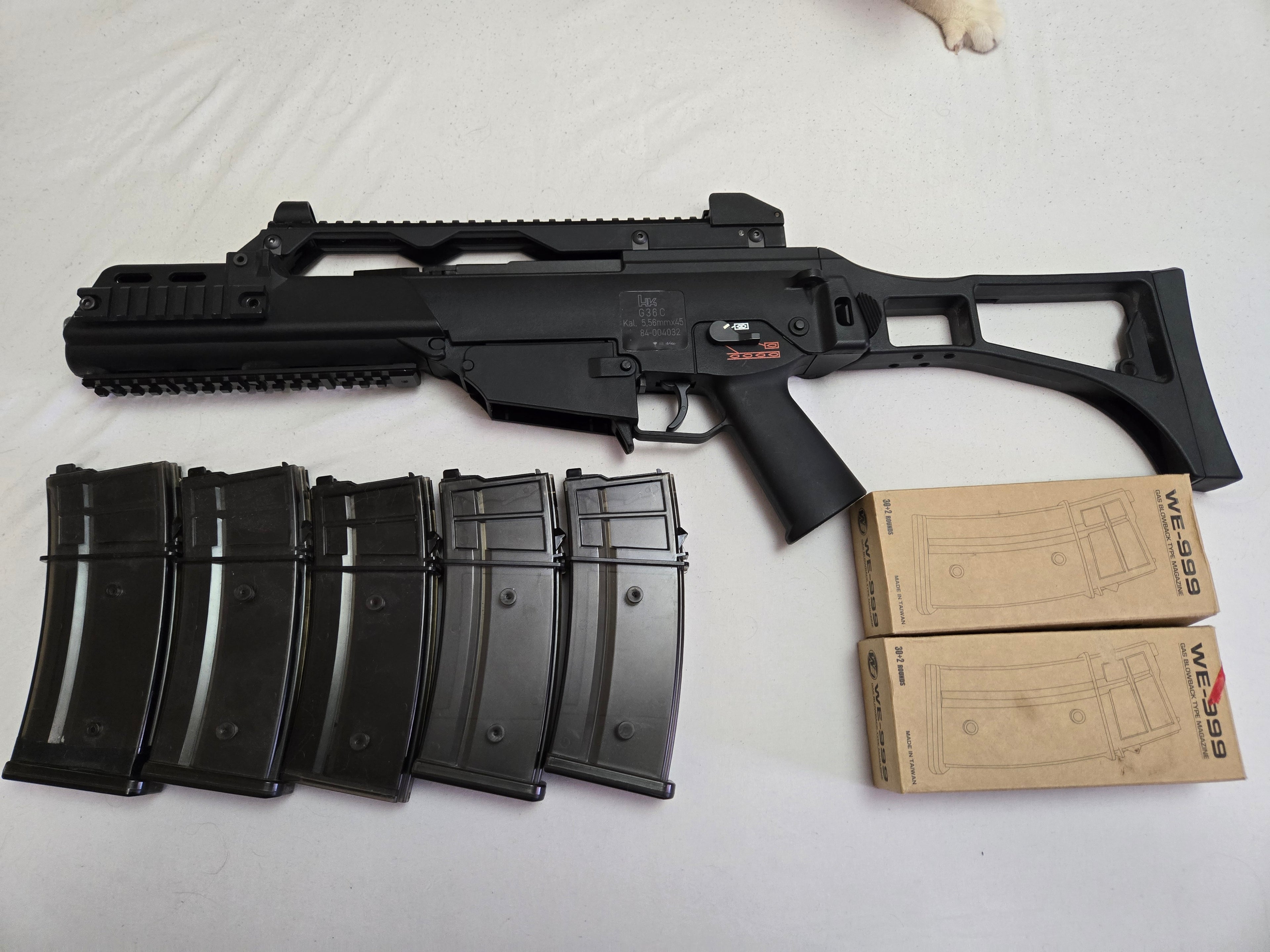 Black rifle with multiple magazines and boxes on a white background